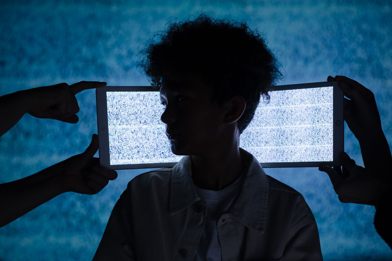 Artistic photo of a childs silhouette framed by digital tablets showing static, exploring technology and isolation.